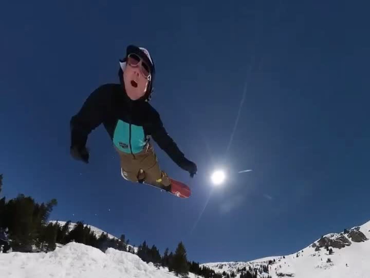 A snowboarder grabbing the board mid-air against a deep blue sky